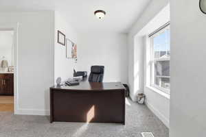 Office area featuring light carpet and baseboards