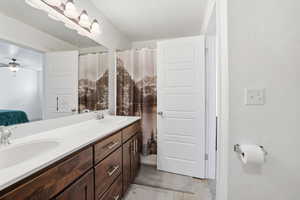 Ensuite bathroom featuring double vanity, a shower with curtain, and a ceiling fan