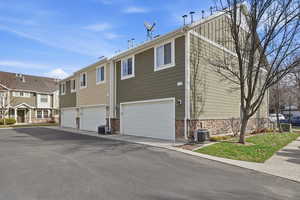 View of front of house featuring a garage, a residential view, driveway, and stone siding