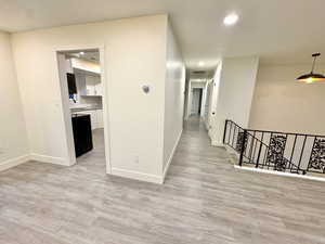 Hall with an upstairs landing, recessed lighting, and light wood-style flooring