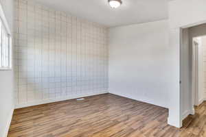 Spare room with tile walls, light wood-type flooring, and an accent wall