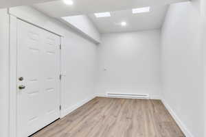 Empty room with light wood-style floors, a baseboard heating unit, and recessed lighting