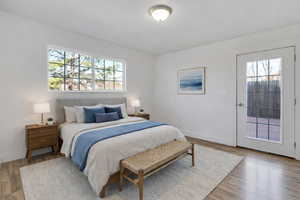 Bedroom with wood finished floors, multiple windows, and access to exterior