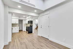 Kitchen featuring stainless steel appliances, white cabinetry, light countertops, light wood-style flooring, and recessed lighting