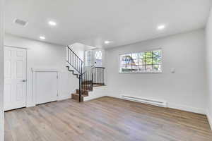 Below grade area featuring baseboard heating, light wood finished floors, and recessed lighting