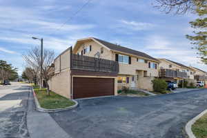 View of front of home featuring brick siding, a residential view, a balcony, asphalt driveway, and a garage