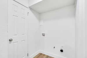 Laundry room with washer hookup, light wood-style floors, gas dryer hookup, and a textured wall