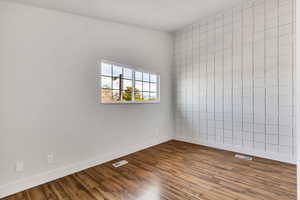 Spare room with dark wood-style flooring and tile walls