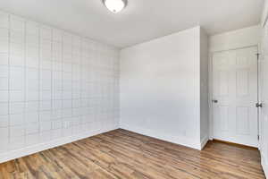 Empty room featuring light wood finished floors and tile walls