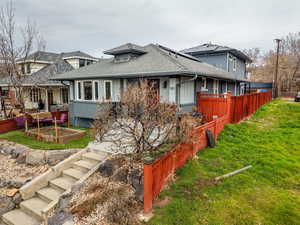 View of front of home featuring a shingled roof, brick siding, a vegetable garden, and solar panels