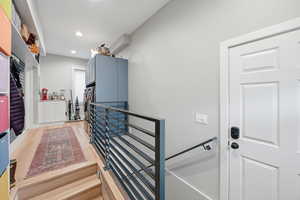 Staircase with wood finished floors and recessed lighting