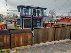 View of front facade with solar panels, a fenced front yard, a gate, an attached garage, and a balcony