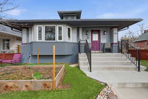 View of front of property featuring a garden, covered porch, and brick siding