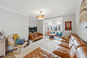 Living area with wood finished floors, ornamental molding, and ceiling fan