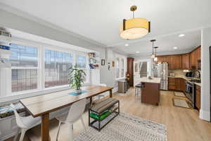 Dining space featuring light wood-type flooring, ornamental molding, and recessed lighting