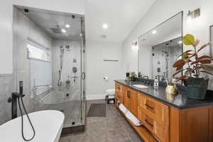 Bathroom featuring vanity, a soaking tub, a shower stall, and dark tile patterned flooring