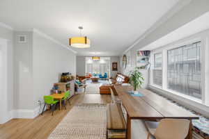 Dining area with light wood-style flooring and ornamental molding