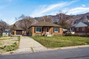 Bungalow-style home with an outdoor structure, a mountain view, brick siding, a garage, and concrete driveway
