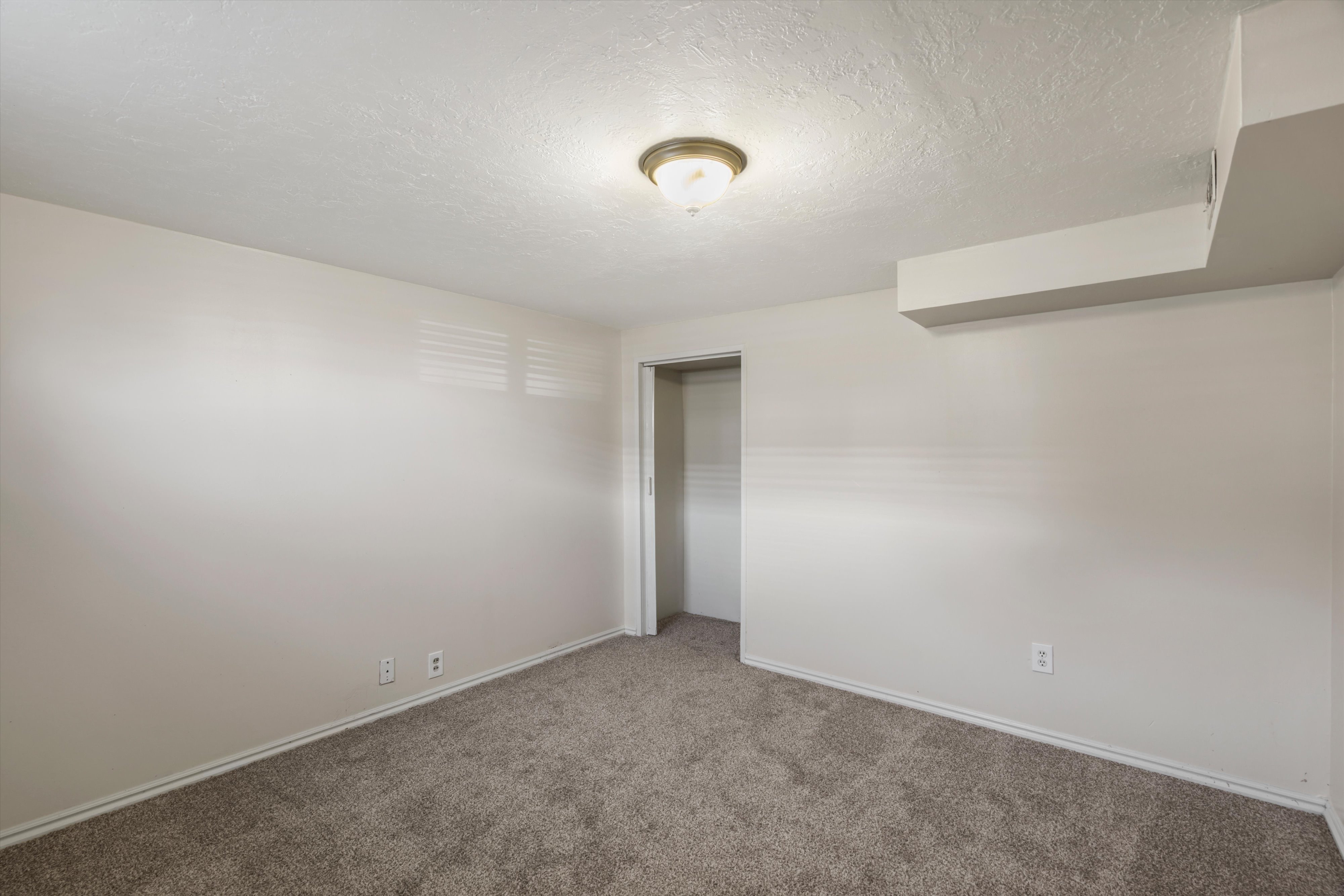 Unfurnished bedroom featuring a textured ceiling, carpet floors, and a closet