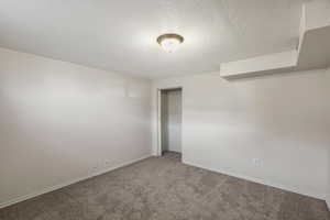 Unfurnished bedroom featuring a textured ceiling, carpet floors, and a closet