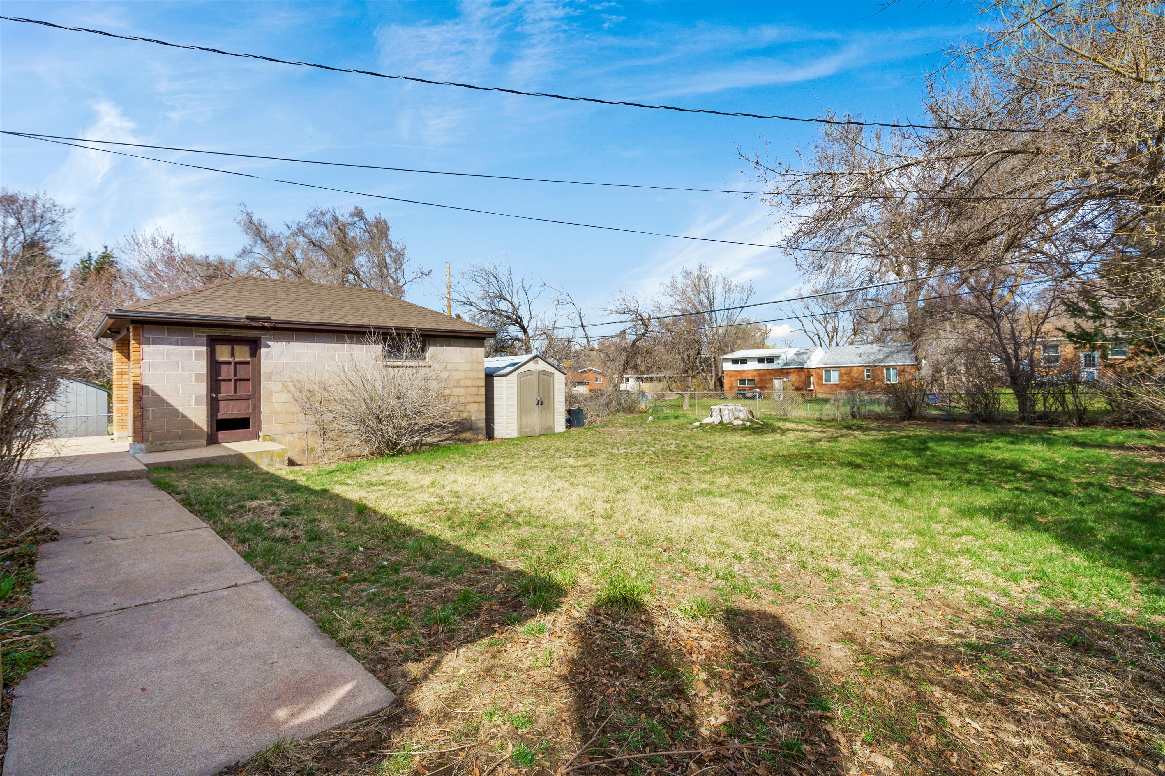 Fenced backyard featuring a storage unit