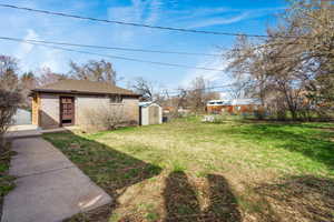 Fenced backyard featuring a storage unit