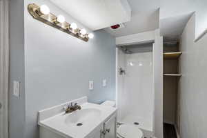 Full bath with vanity, a stall shower, and a textured ceiling