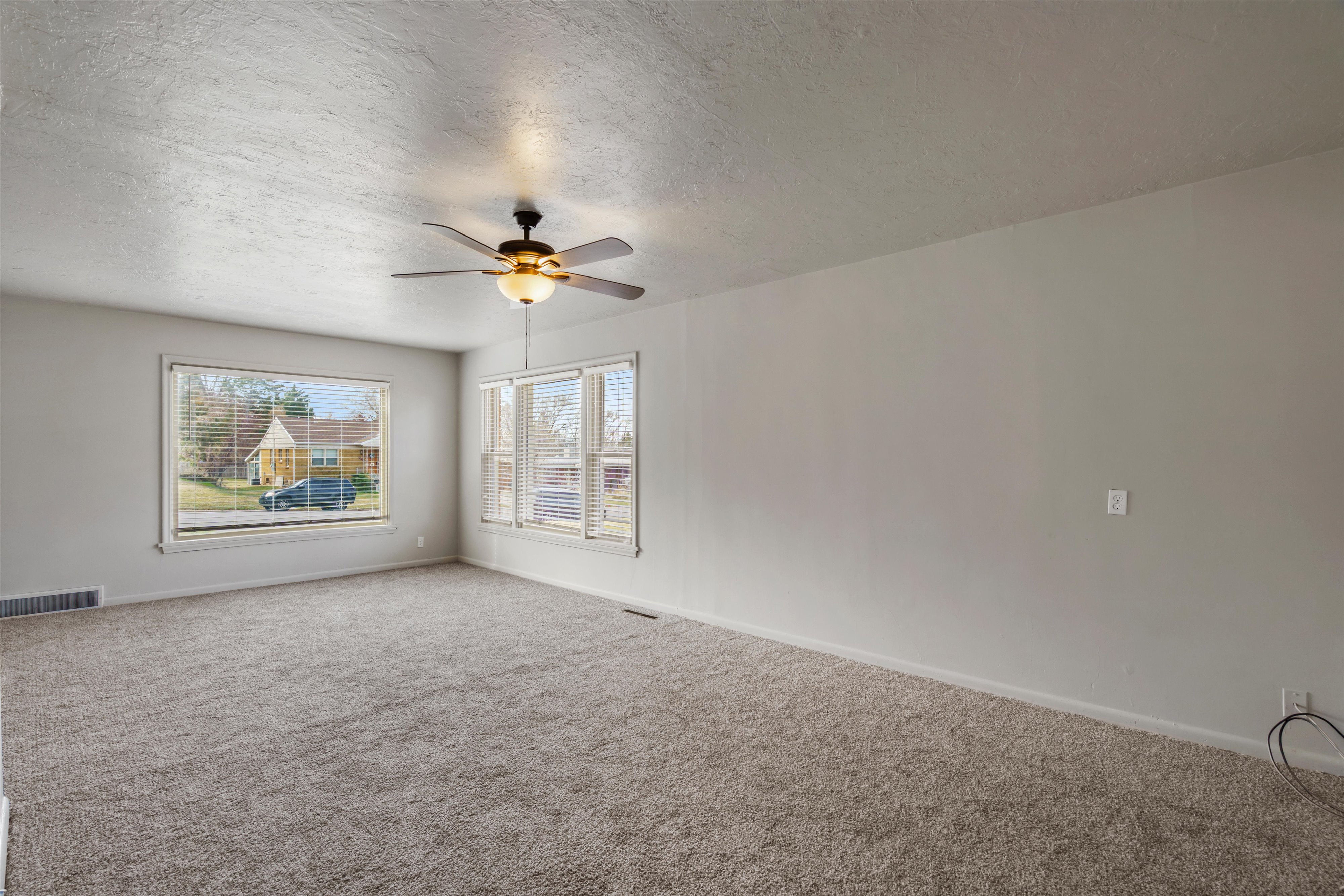 Carpeted spare room featuring a textured ceiling and a ceiling fan