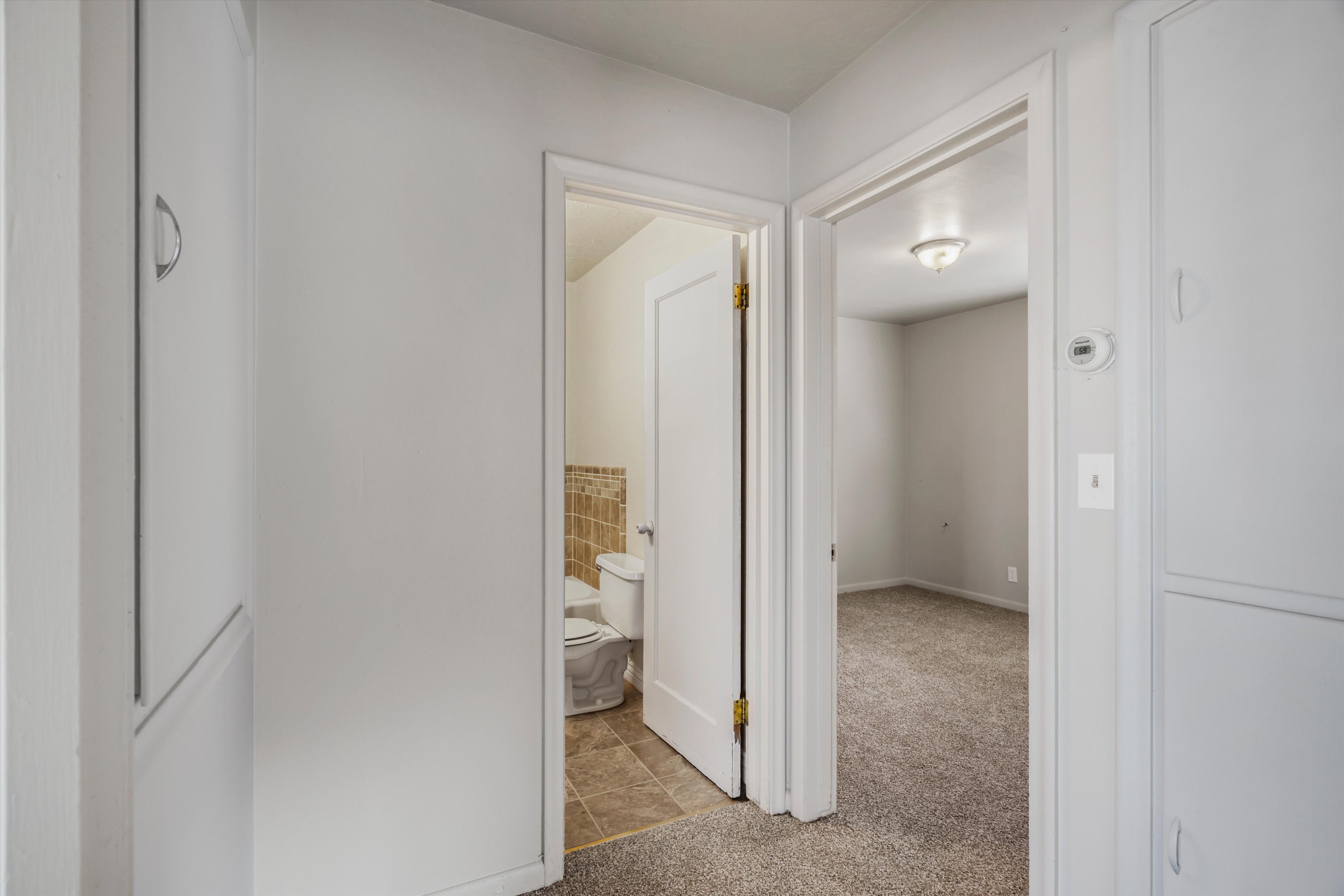 Corridor featuring light carpet and light tile patterned floors