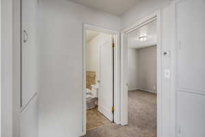 Corridor featuring light carpet and light tile patterned floors