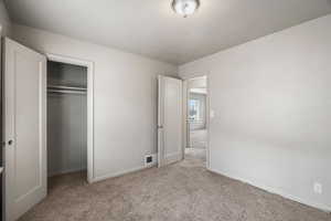 Unfurnished bedroom featuring light carpet and a closet