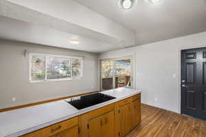 Kitchen with light countertops, black electric cooktop, light wood finished floors, and wood finish cabinetry