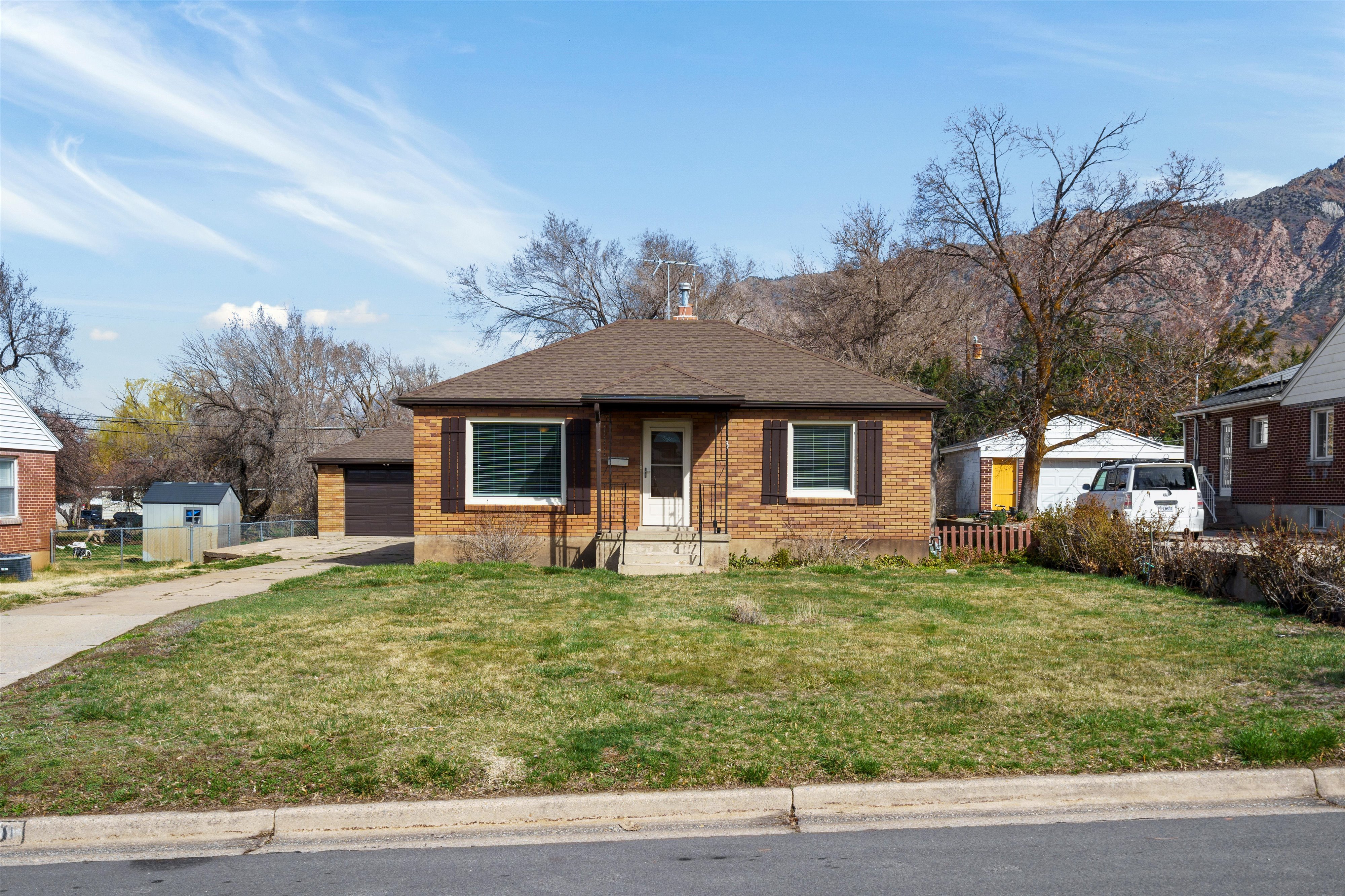 Bungalow-style house featuring brick siding, a shingled roof, a garage, a chimney, and a mountain view