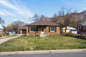 Bungalow-style house featuring brick siding, a shingled roof, a garage, a chimney, and a mountain view