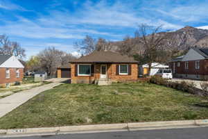 View of front of home with a front yard, brick siding, and roof with shingles