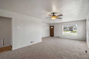 Carpeted empty room with a textured ceiling and ceiling fan