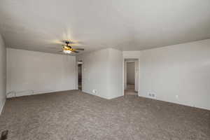 Carpeted empty room featuring a ceiling fan and baseboards