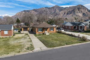 View of front of property with a residential view, a mountain view, a garage, an outbuilding, and a front lawn