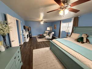 Bedroom with dark wood finished floors, a ceiling fan, and a textured ceiling