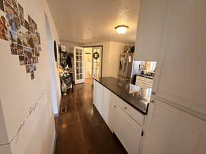 Hall featuring dark wood-style flooring and a textured ceiling