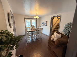 Dining area featuring a textured ceiling, dark wood-style flooring, and suspended lighting