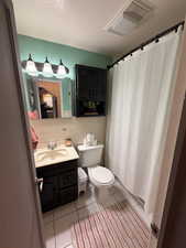 Bathroom with vanity, a shower with curtain, a textured ceiling, and light tile patterned floors