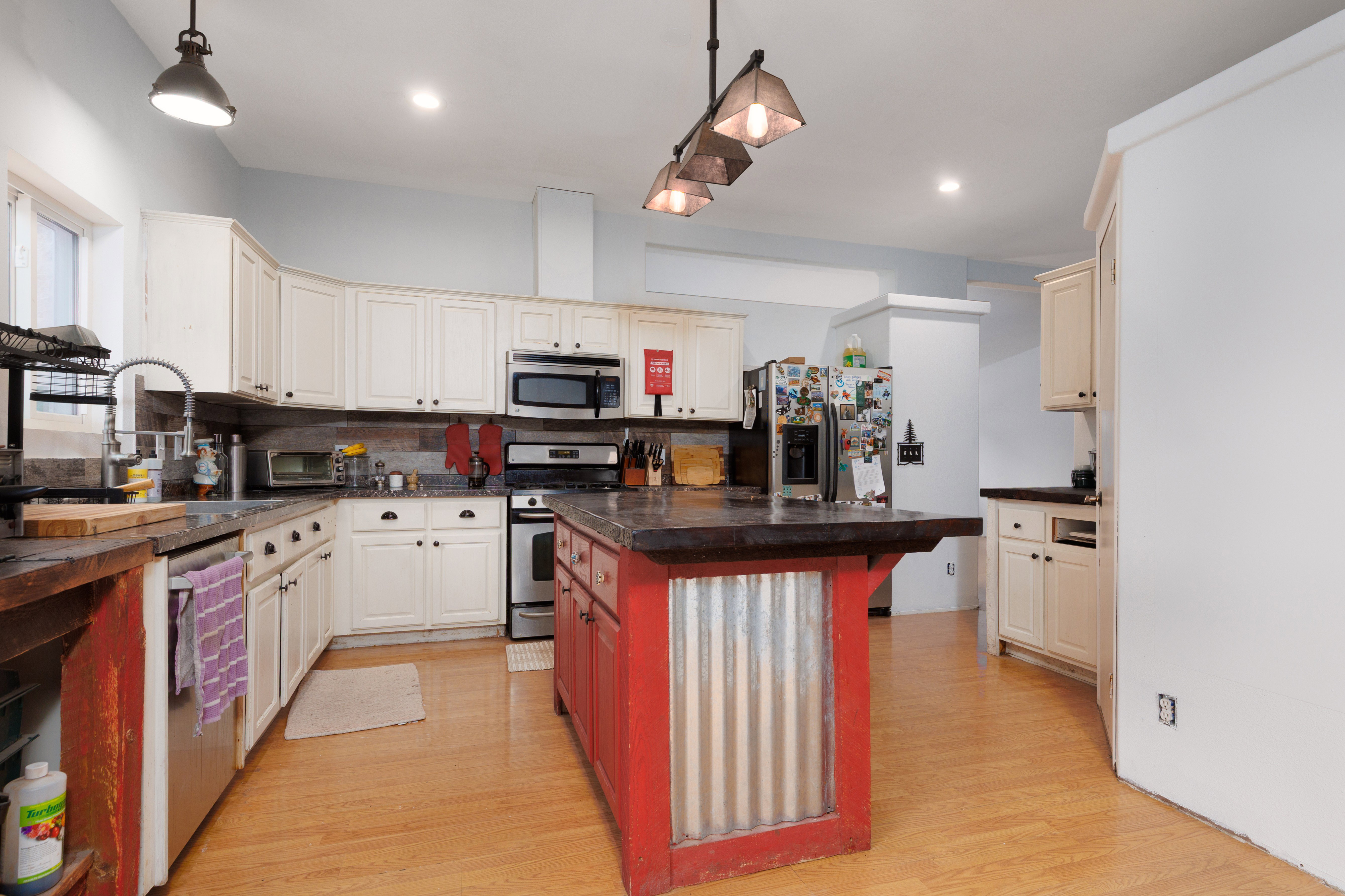 Kitchen featuring stainless steel appliances, a center island, light wood-type flooring, backsplash, and two tone color scheme