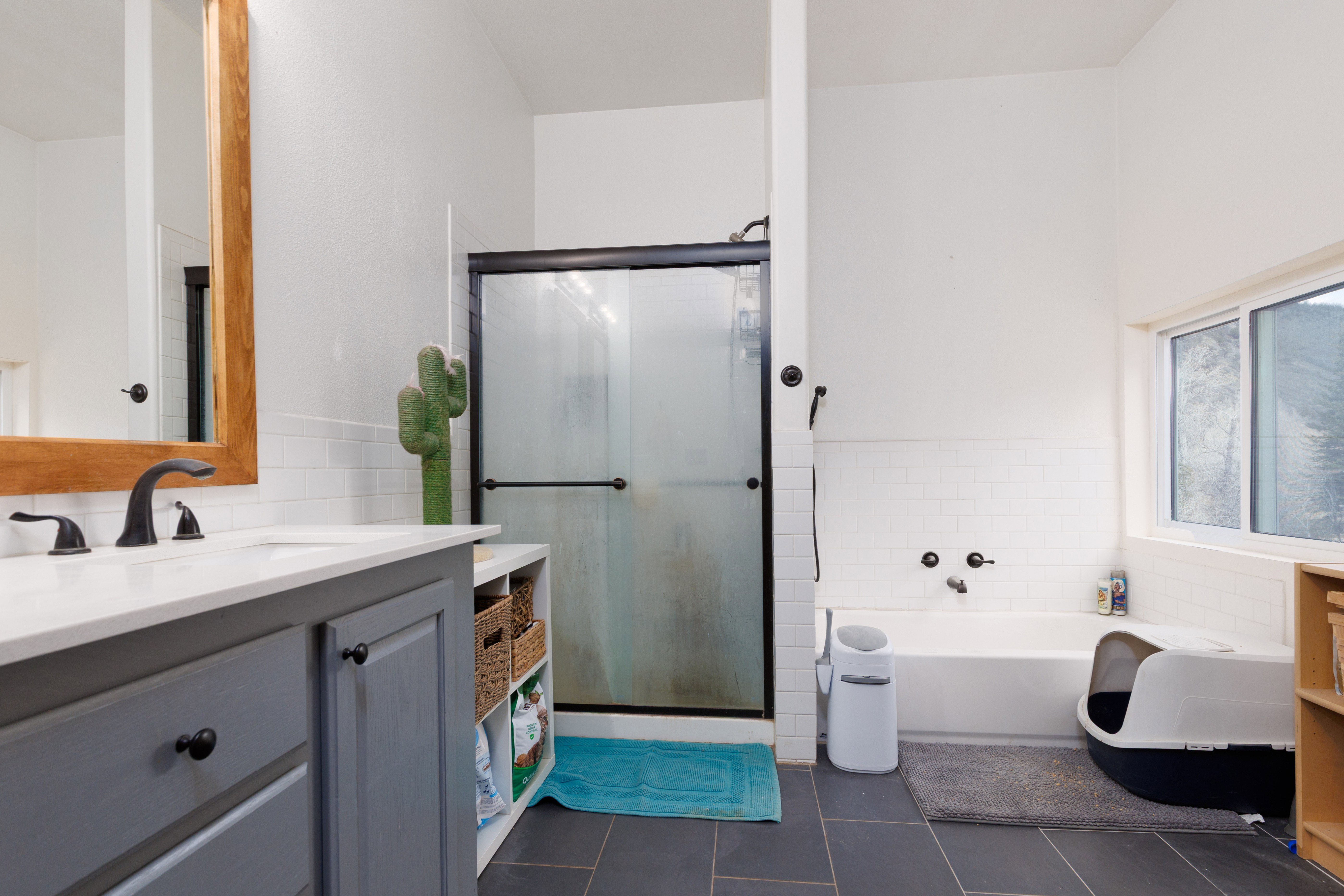 Bathroom featuring vanity, a bath, a stall shower, dark tile patterned flooring, and tile walls