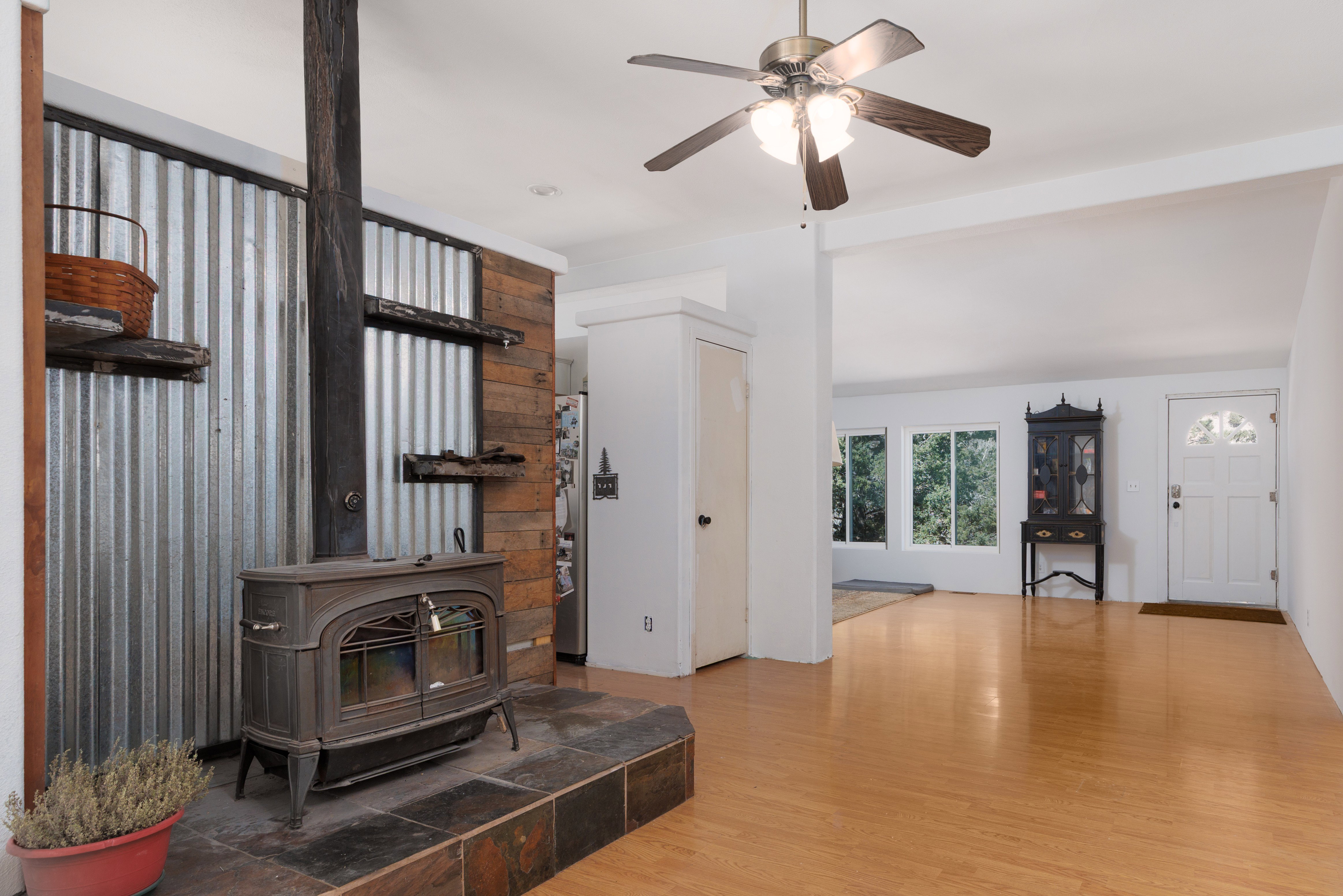 Living area featuring ight wood-style floors, ceiling fan, and a wood stove