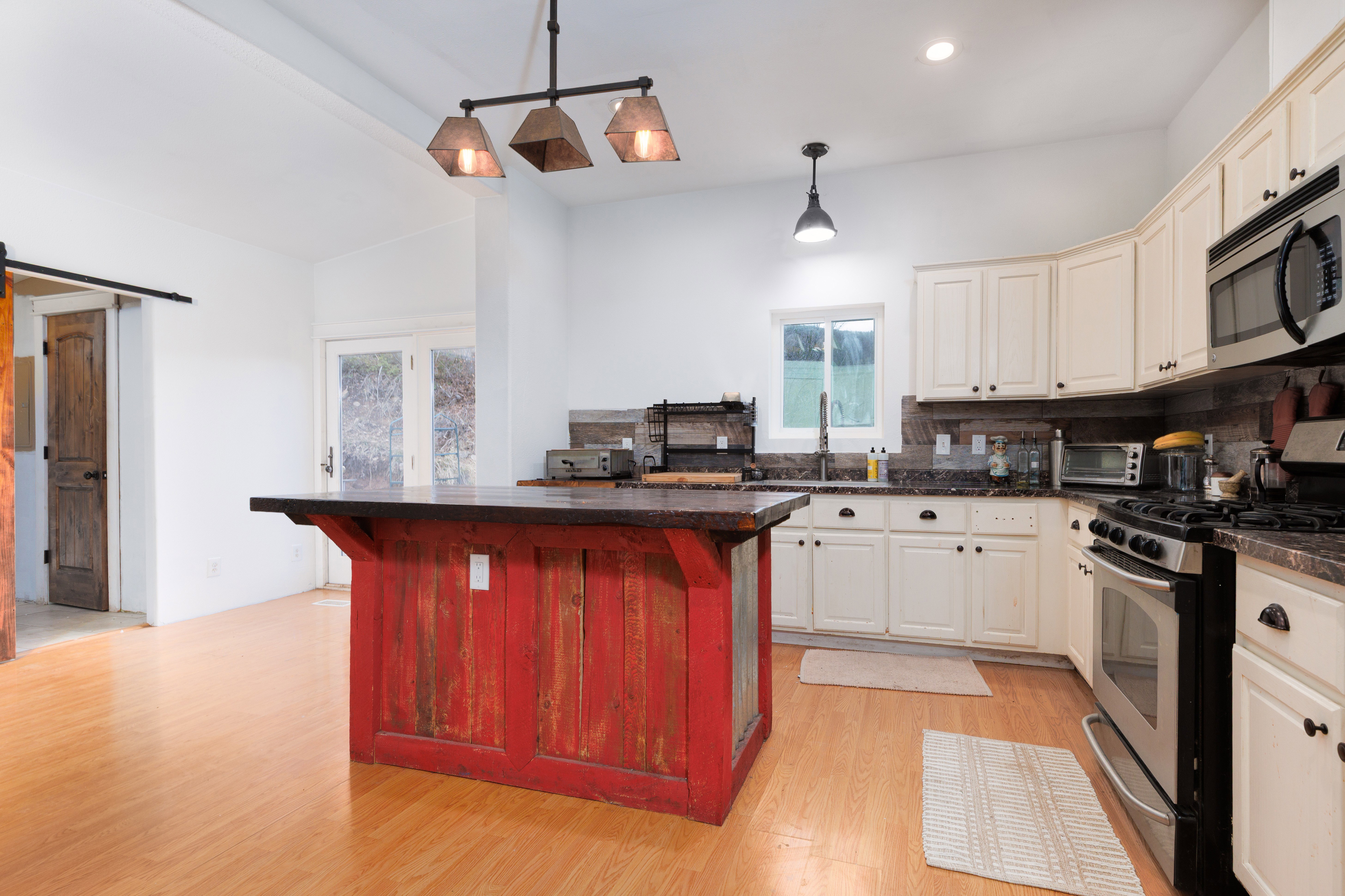 Kitchen featuring stainless steel appliances, a center island, light wood-type flooring, backsplash, and two tone color scheme