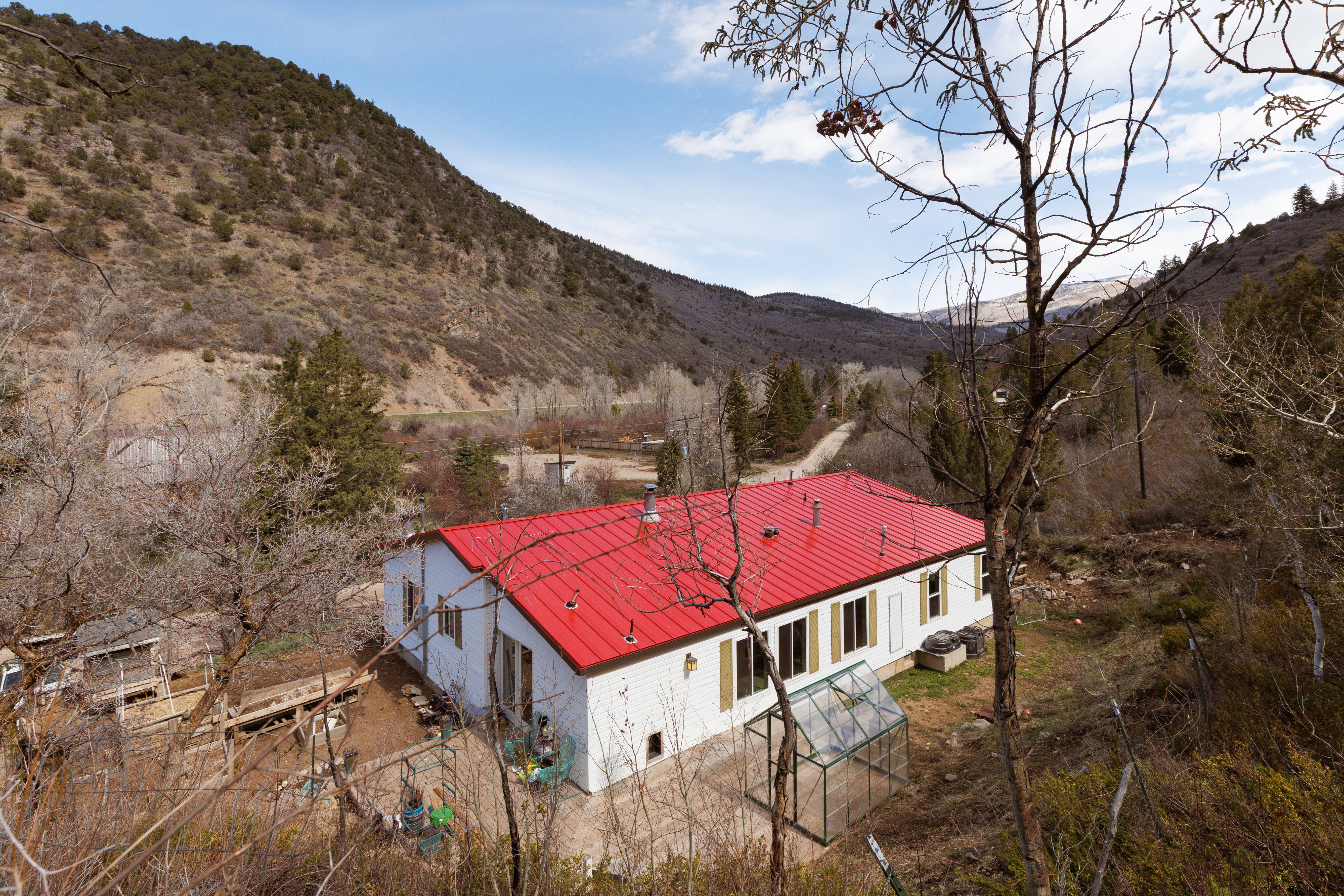 View of house with a metal roof, accessory building, greenhouse and a deck with mountain view