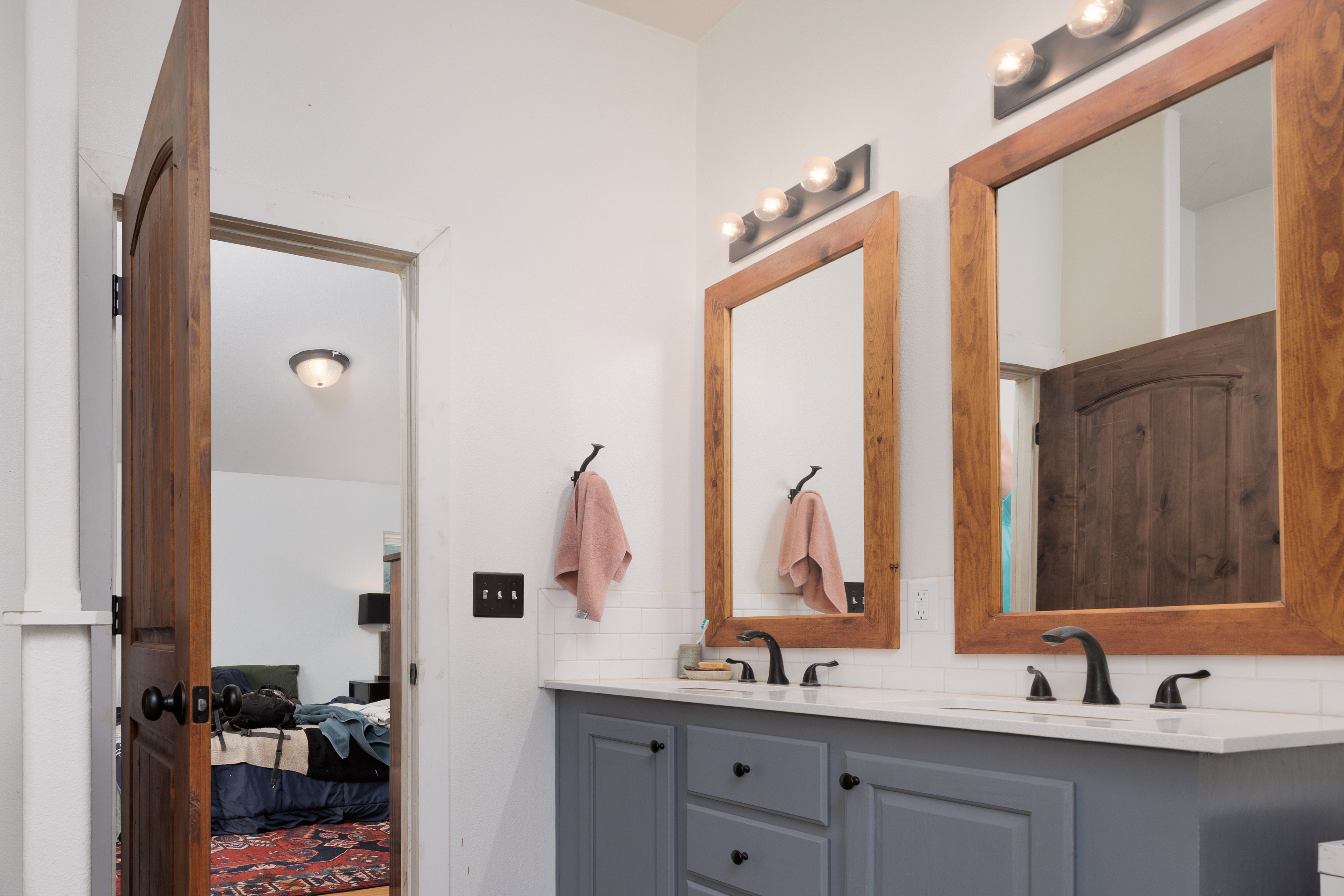 Full bath featuring double vanity, decorative backsplash, and connected bedroom