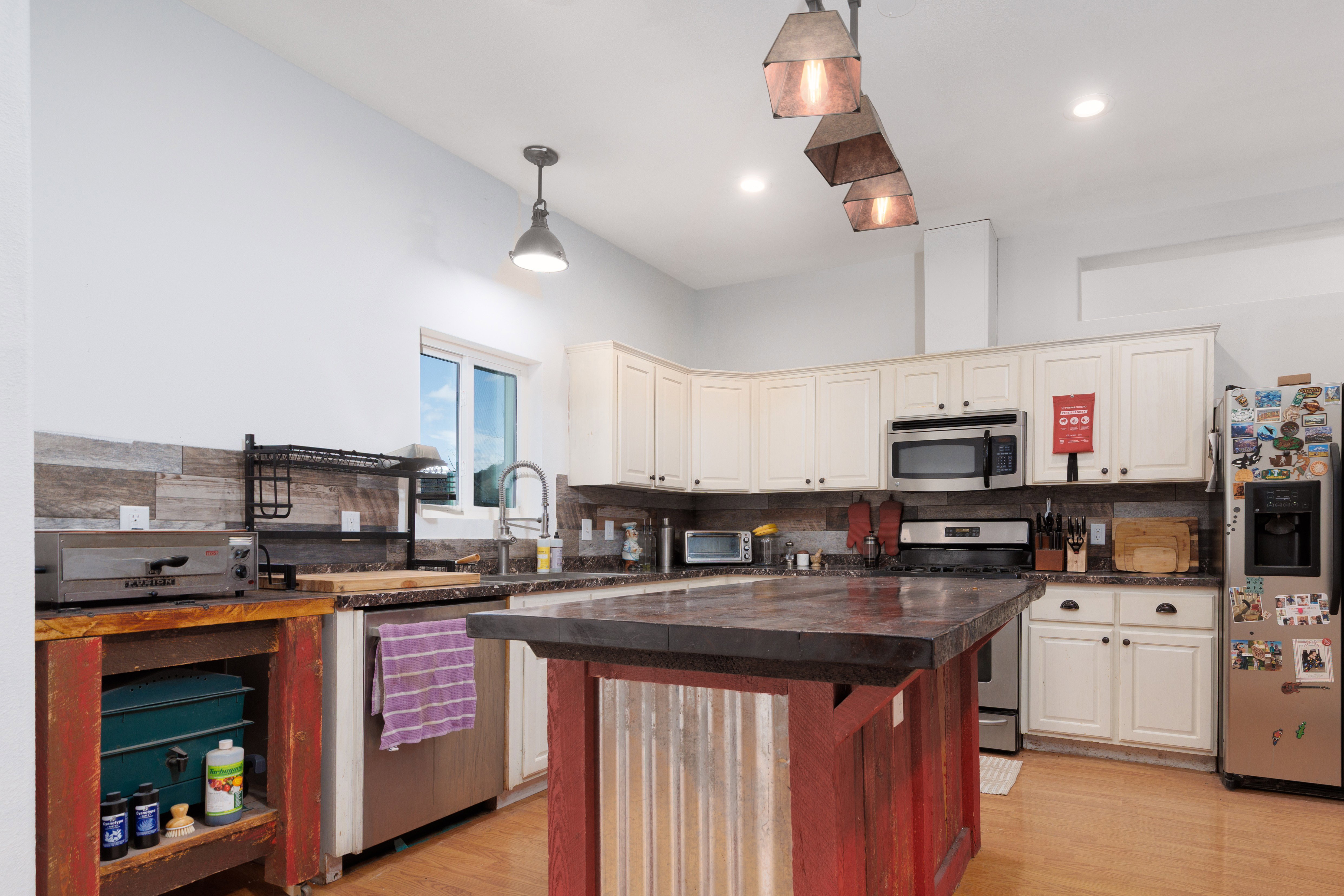 Kitchen featuring stainless steel appliances, a center island, light wood-type flooring, backsplash, and two tone color scheme