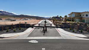 View of asphalt road with sidewalks, a gated entry, a gate, a residential view, and a mountain view